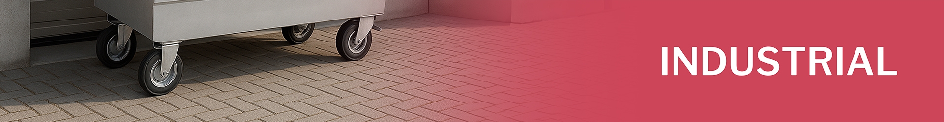 Heavy industrial casters under metal container on pavement with text 'INDUSTRIAL' on red background